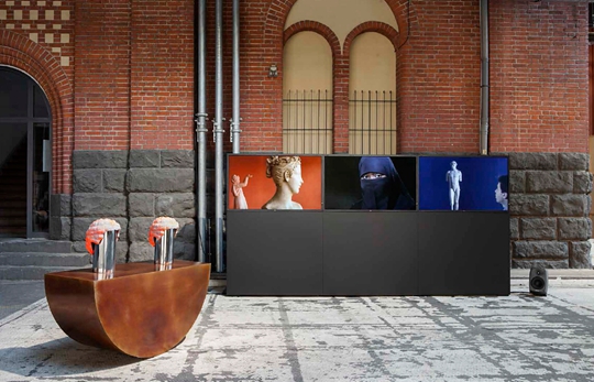 View of “Something Always Happens Keeps Happening” Art Berlin Contemporary, 2014 Left: Rolling Beating, 2014 Colored bronze and car tire, 127 x 48 x 22 cm Right: Action, 2014, 3-channel video, 10 min Courtesy Kraupa-Tuskany Zeidler and the artist PHOTO: Andrea Rossetti